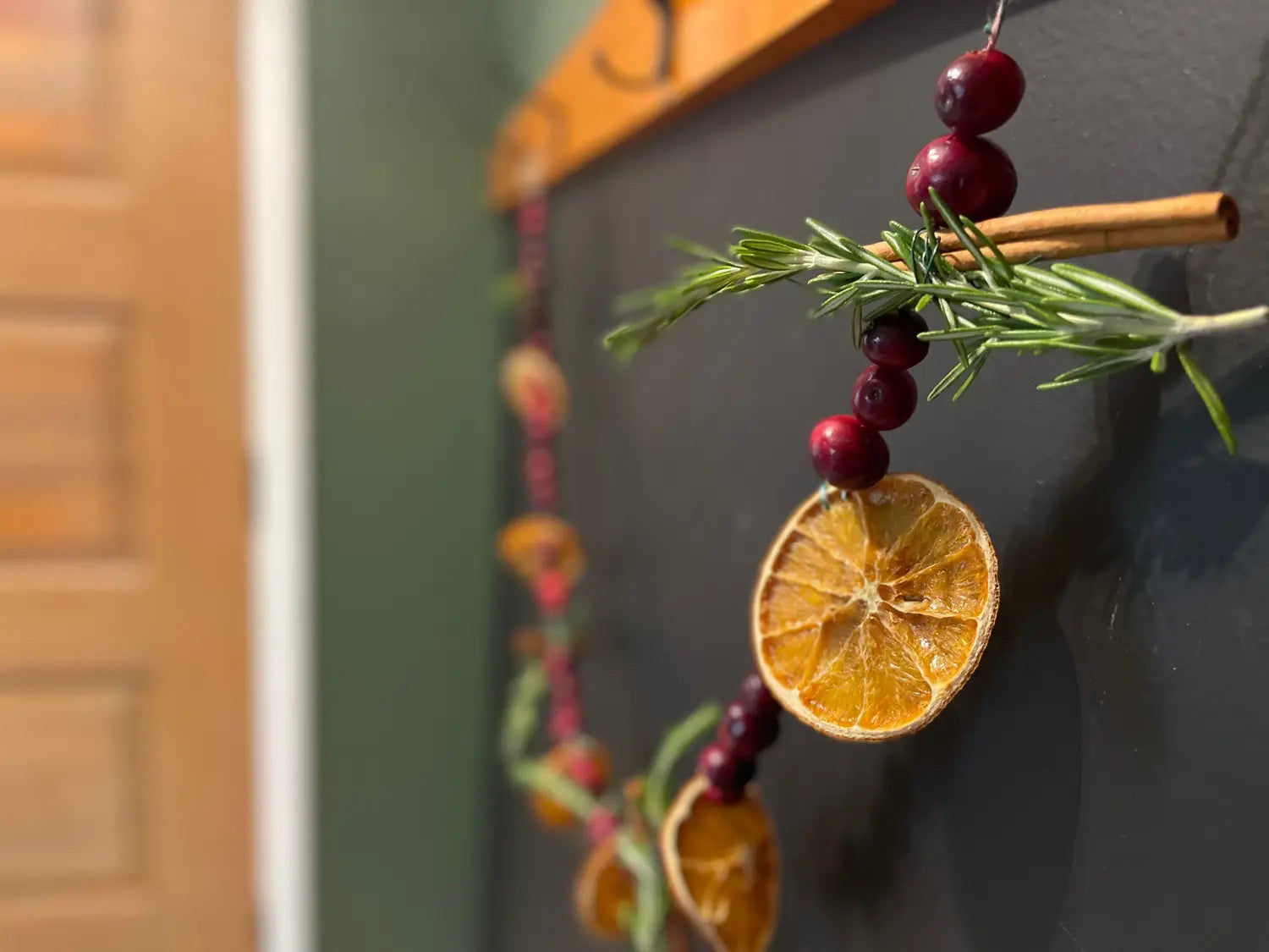 Dried orange slice and cranberries on a decorative garland with greenery for winter.