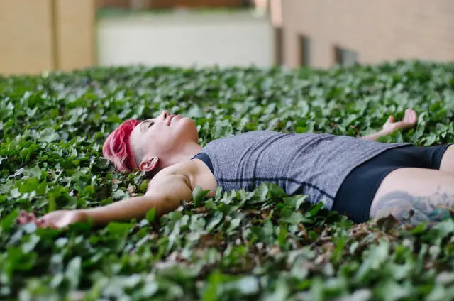 Person with pink hair lounging in ivy, embracing relaxation on National Relaxation Day.