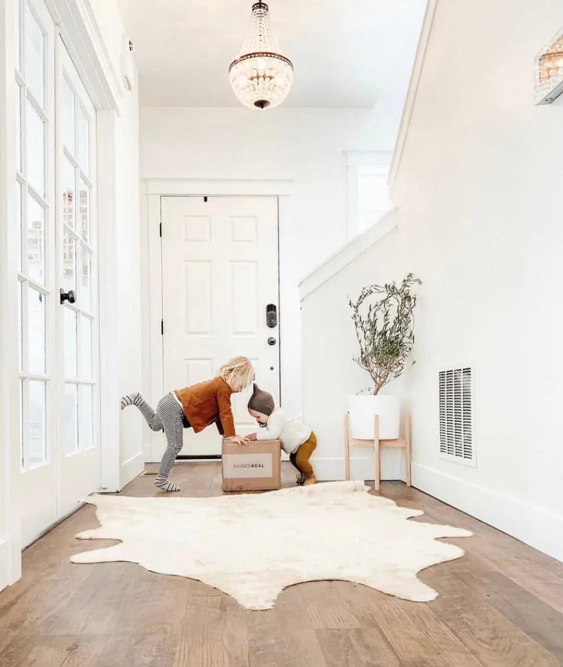 White cowhide rug on wooden floor showcasing a chic Raised Real collaboration style.