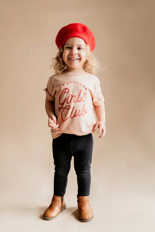 Cheerful child in pink Girl Club tee and red beret, firm believers in polished prints.