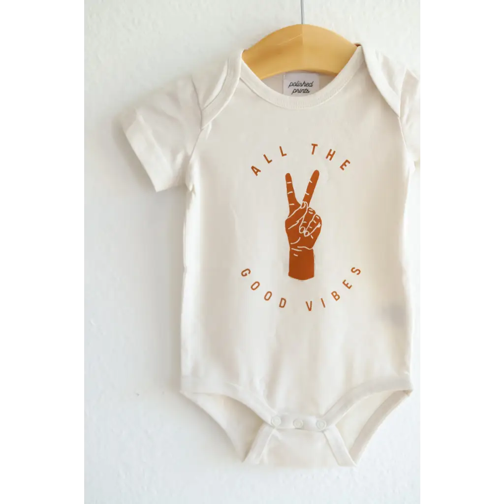 White Good Vibes Organic Cotton Baby Onesie with peace sign graphic in brown