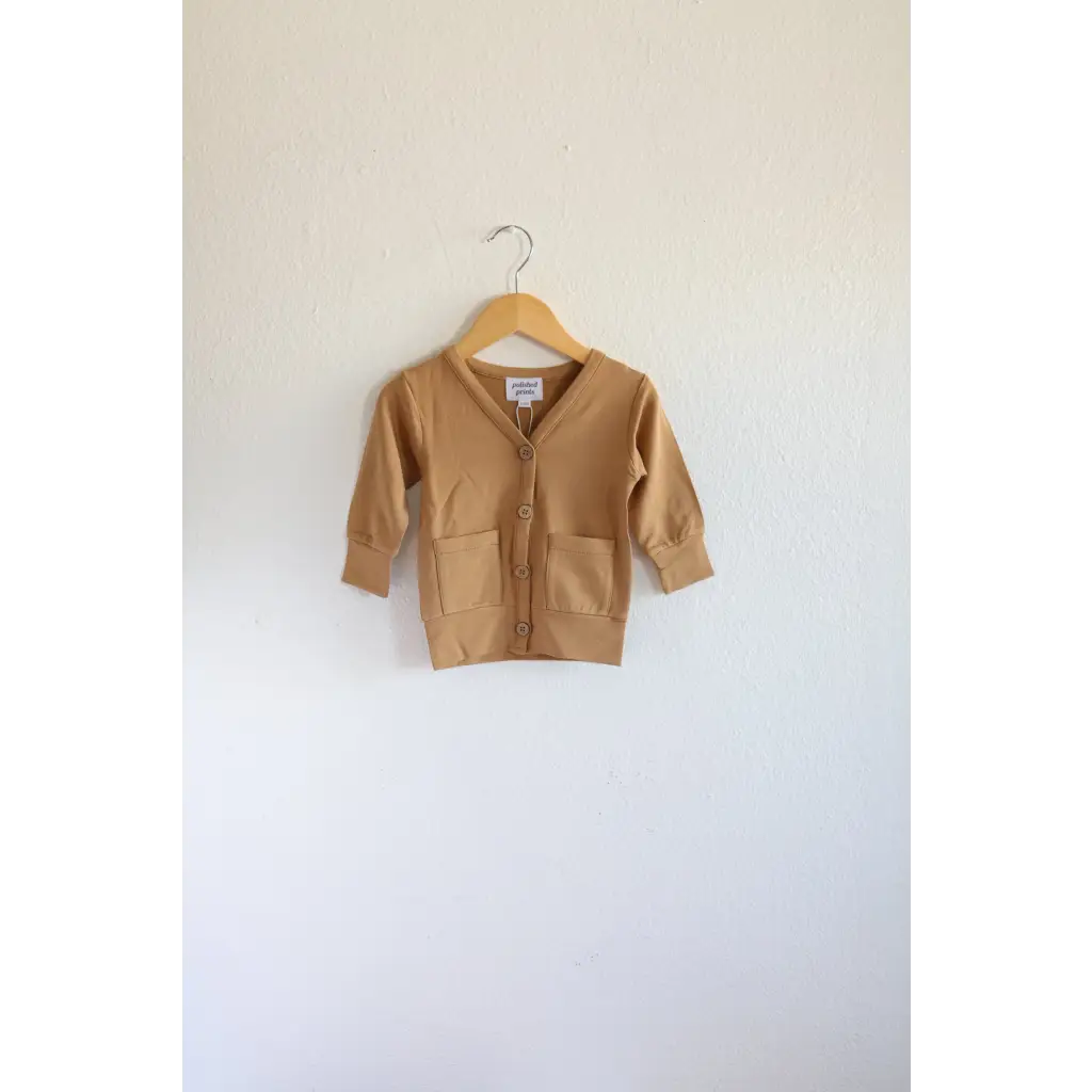 Tan Buttery Soft Baby Grandpa Cardigan sweater hanging on a wooden hanger for holiday season