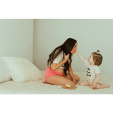 Tender moment between parent and baby in good organic cotton bodysuit on bed