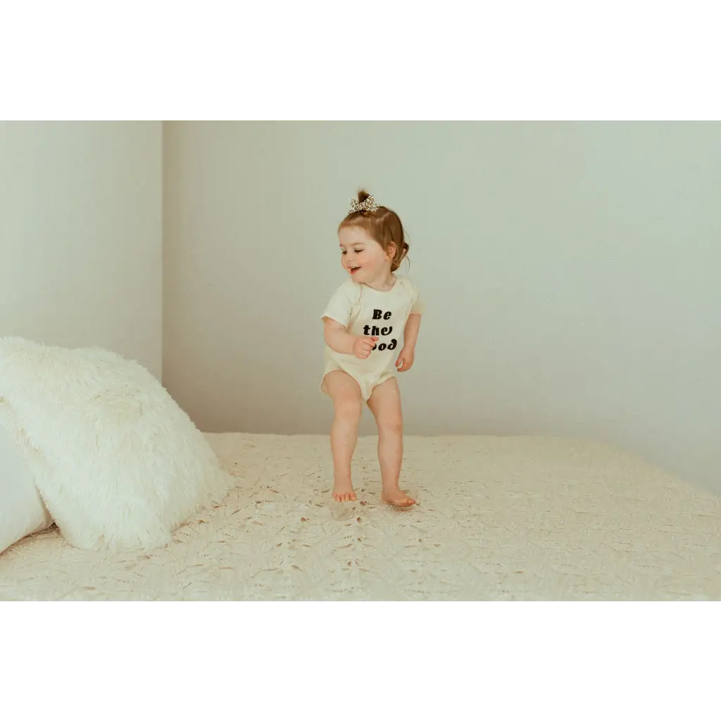 Toddler in a white t-shirt and diaper, modeling the Be the Good Organic Cotton Baby Bodysuit