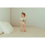 Toddler in a white t-shirt and diaper, modeling the Be the Good Organic Cotton Baby Bodysuit