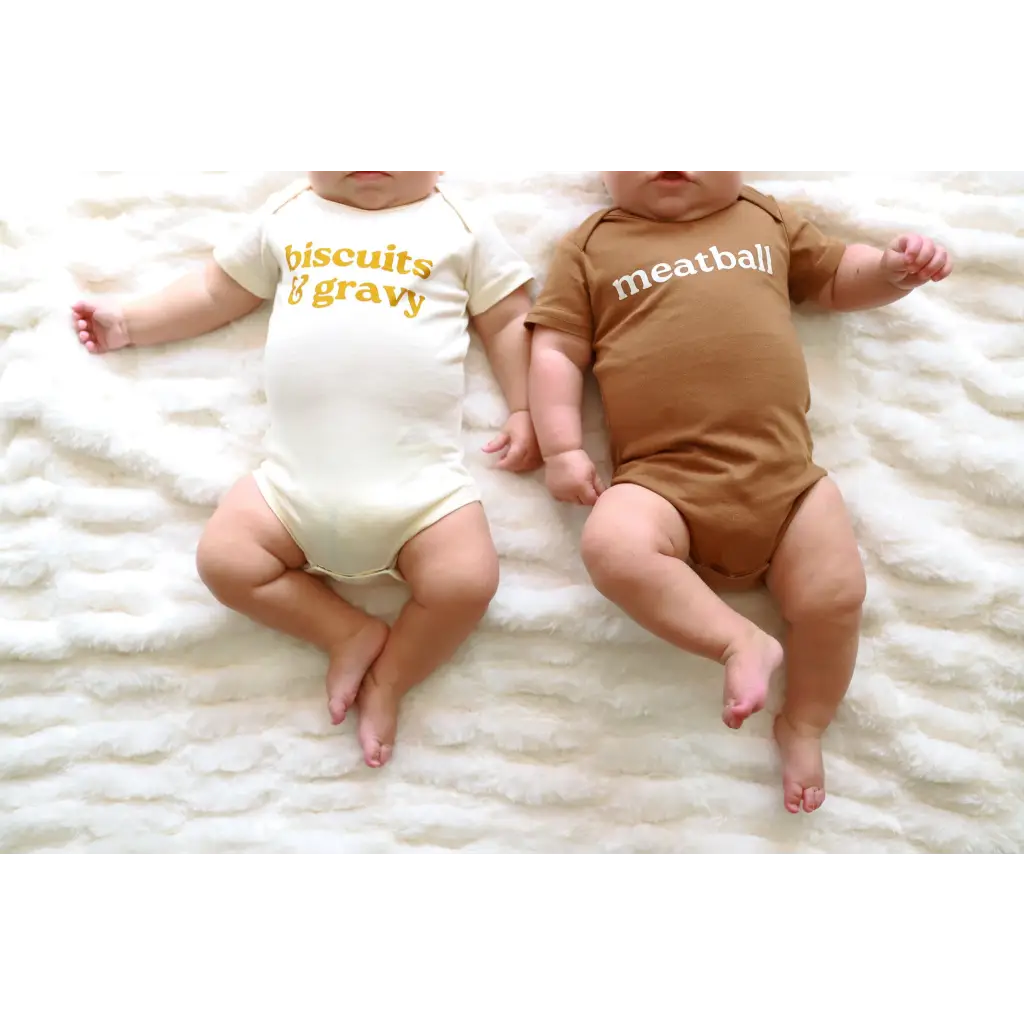 Two babies in coordinating Biscuits and Gravy and Meatball baby onesies in organic cotton