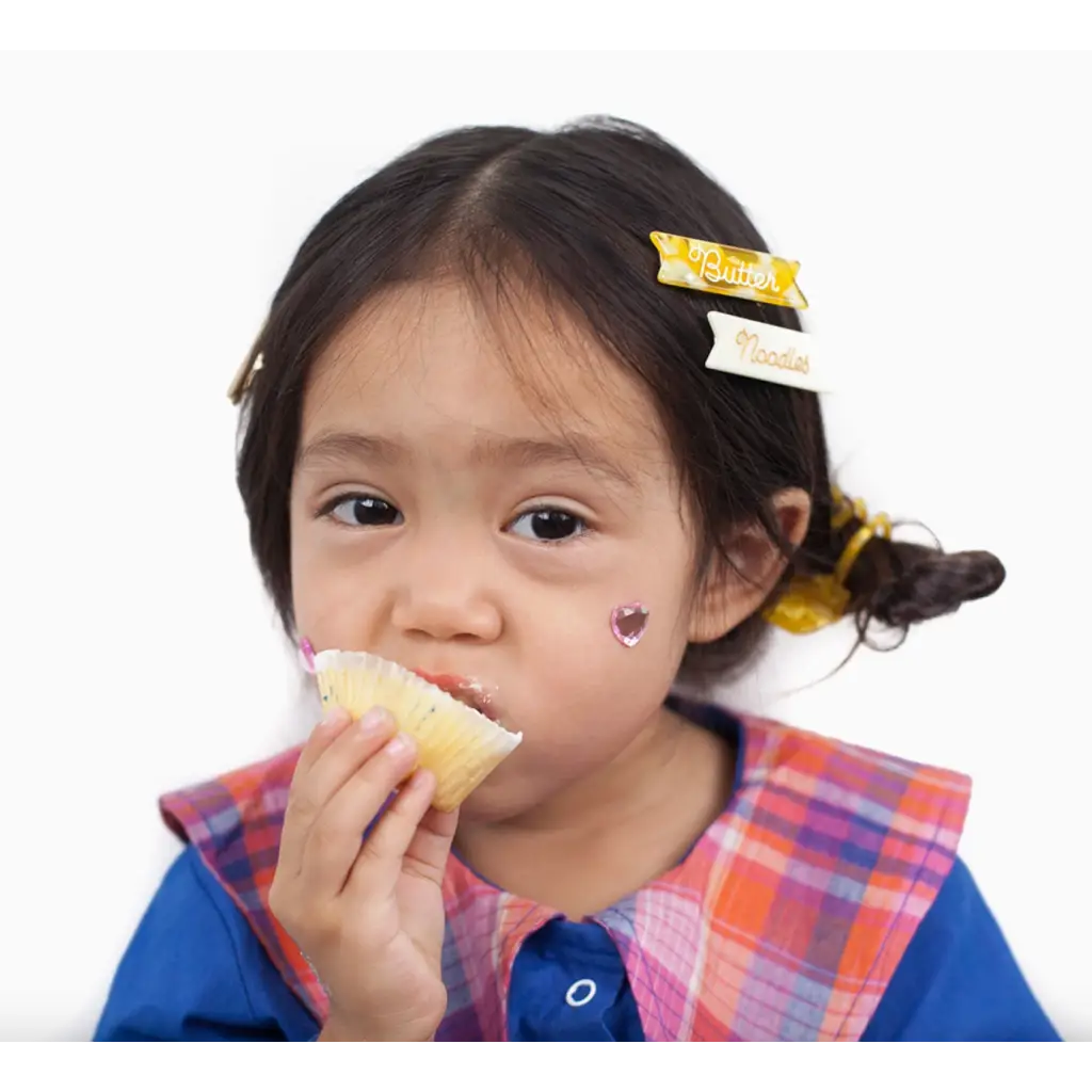 Child enjoying a cupcake in a plaid bib with Butter Noodles Hair Clips in her hair