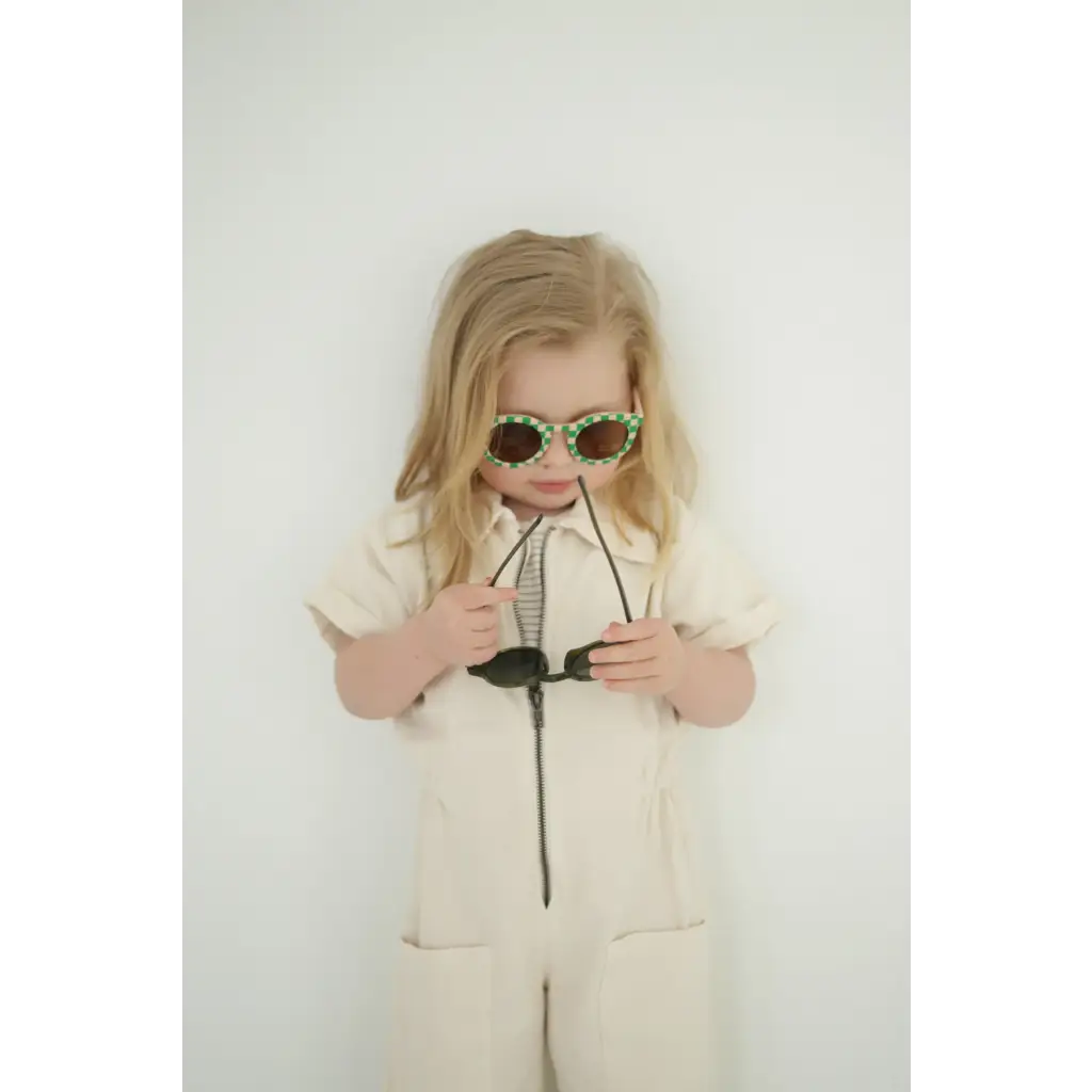 Child in beige jumpsuit rocking checkered baby kids sunnies for a cool style
