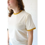 Cream-colored organic cotton ringer tee with mustard yellow trim and polished prints