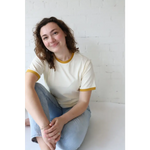 Woman in mustard classic women’s ringer tee made from organic cotton with polished prints