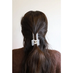 White plastic hair clip holding dark brown hair in a ponytail for effortless styling