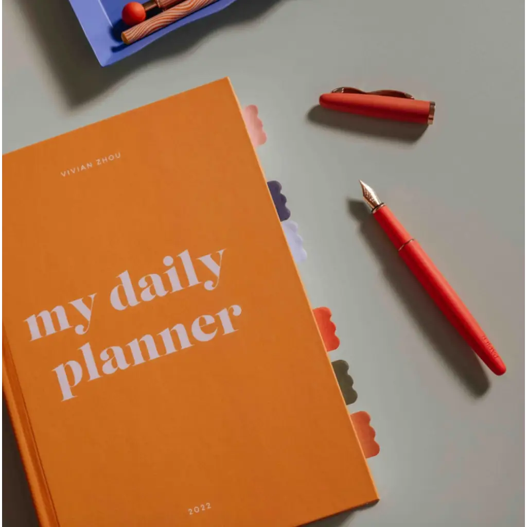 Orange daily planner with a red fountain pen showcasing Cloud Sticky Index Tabs and sticky index tabs