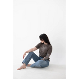 Person in a brown t-shirt and blue jeans chilling in a Minimalist Graphic Tee with free shipping