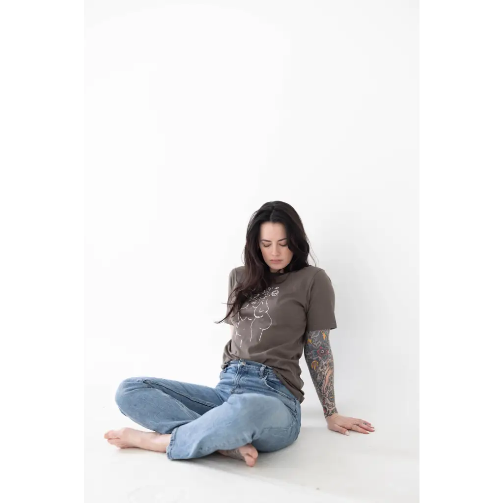 Person in brown graphic tee and blue jeans, showcasing minimalist style with free shipping