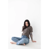 Person in brown graphic tee and blue jeans, showcasing minimalist style with free shipping
