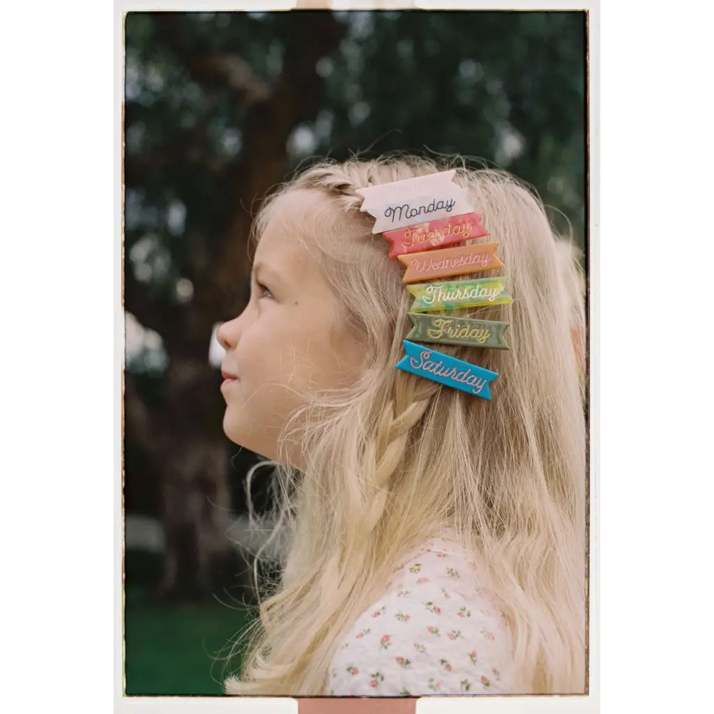 Colorful rainbow hair clips with cursive ink inlay on blonde hair and gold alligator clips
