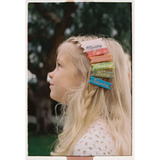 Colorful rainbow hair clips with cursive ink inlay on blonde hair and gold alligator clips