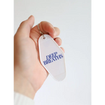 White tag with DEEP BREATHS in blue on the Deep Breaths Vintage Hotel Keychain