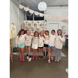 Group of happy girls at craft bar party with matching cream shirts, perfect for bar host events