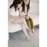 Two kids in casual wear on a couch showcasing Ditsy Rainbow Leggings by Polished Prints