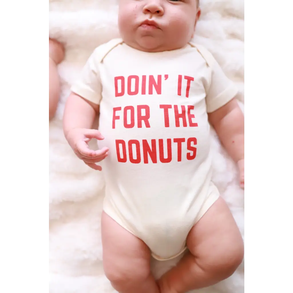 Playful baby onesie in organic cotton featuring pink text Doin It For The Donuts