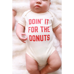Playful baby onesie in organic cotton featuring pink text Doin It For The Donuts