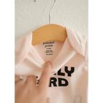 White Early Bird Onesie on a wooden hanger, perfect for adorable early wake-up calls