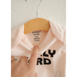 White Early Bird Onesie on a wooden hanger, perfect for adorable early wake-up calls