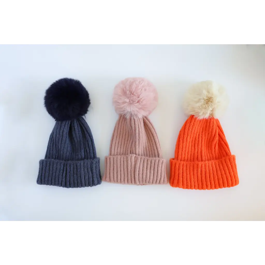 Three stylish Eloise Pom Pom Beanies for kids in navy, pink, and orange colors