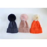 Three stylish Eloise Pom Pom Beanies for kids in navy, pink, and orange colors