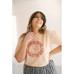 Beige Empowered Women graphic t-shirt with red design, styled with a checkered skirt