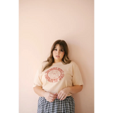 Person in a cream Empowered Women graphic t-shirt and gingham skirt, stylish and fun