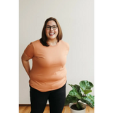 Cheerful person in peach tee showcasing the Toasted Unisex Adult Tee in organic cotton