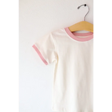 White everyday ringer tee with pink trim hanging on a wooden hanger for kids