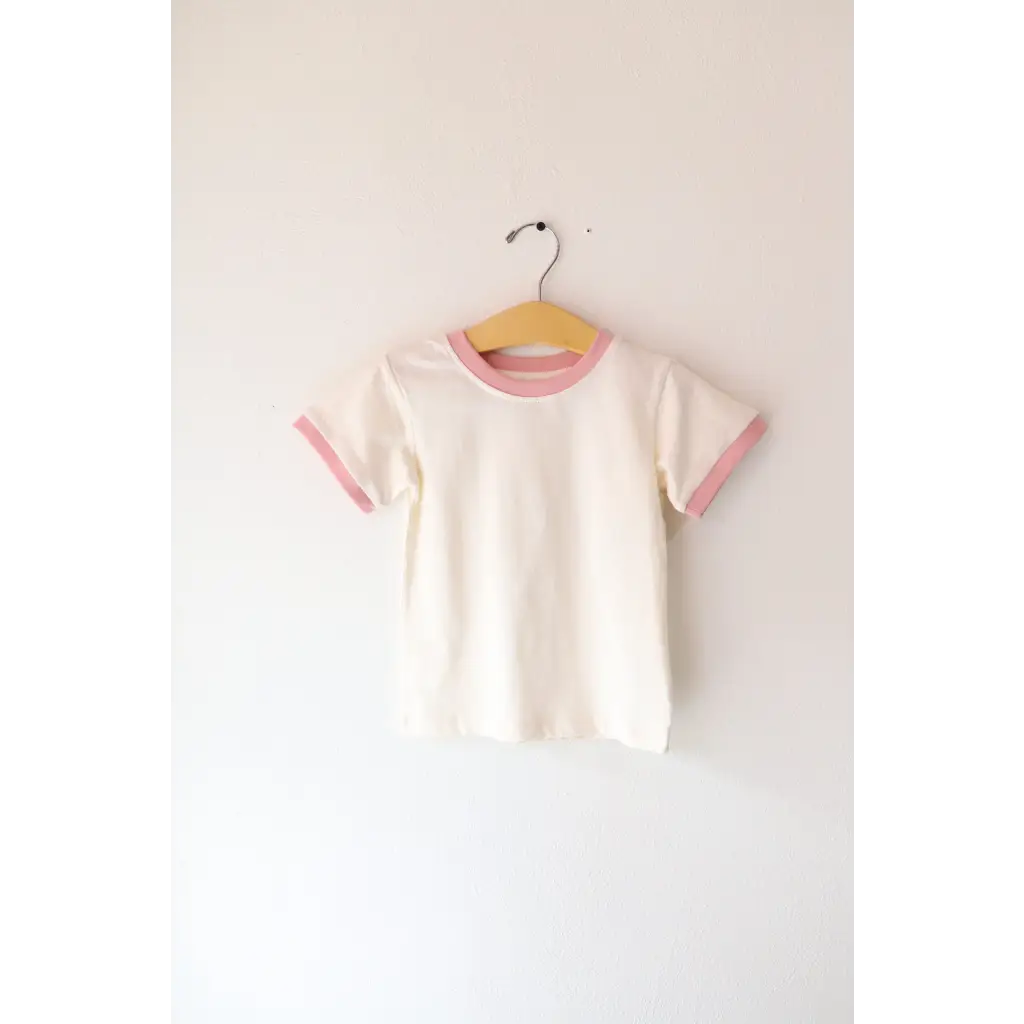 White basic everyday ringer tee with pink trim hanging on a stylish hanger