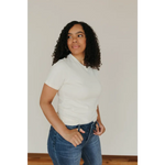 Person in white Natural Unisex Adult Tee made with organic cotton, styled with blue jeans