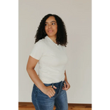 Person in white Natural Unisex Adult Tee made with organic cotton, styled with blue jeans
