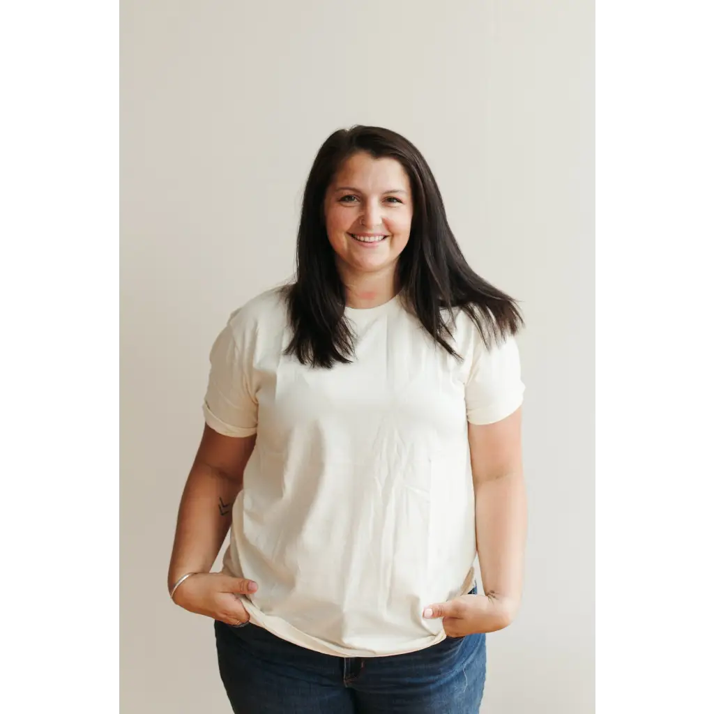 Woman in a white t-shirt and blue jeans, flaunting a Natural Unisex Adult Tee in Organic Cotton