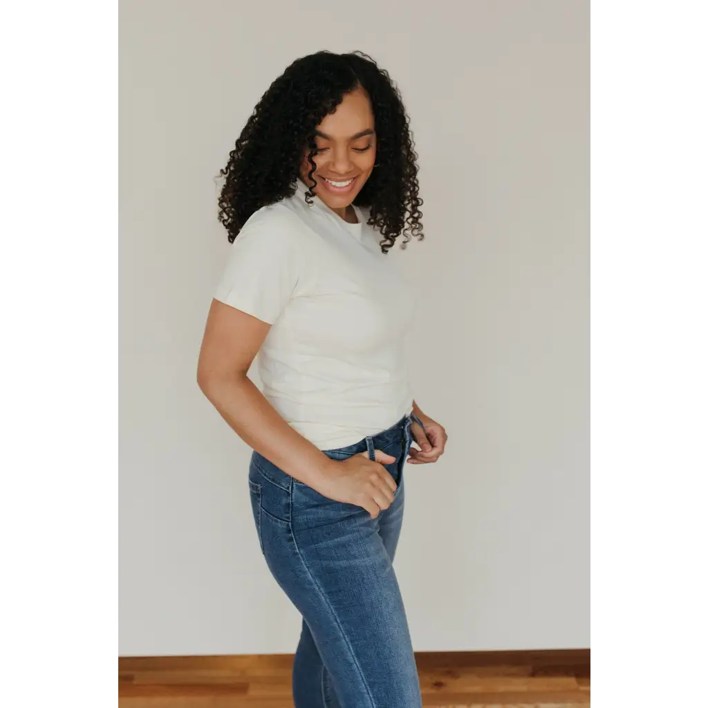 Person with curly black hair wearing a Natural Unisex Adult Tee made of organic cotton