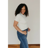 Person with curly black hair wearing a Natural Unisex Adult Tee made of organic cotton