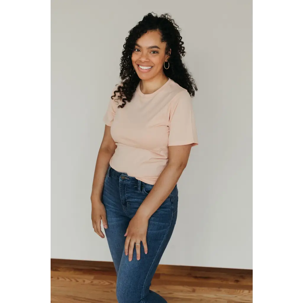 Smiling person in a Peach Unisex Adult Tee made with organic cotton and blue jeans