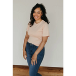 Smiling person in a Peach Unisex Adult Tee made with organic cotton and blue jeans