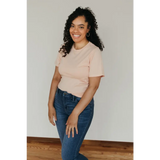 Smiling person in a Peach Unisex Adult Tee made with organic cotton and blue jeans
