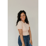 Smiling person in a beige Peach Unisex Adult Tee made with organic cotton and blue jeans