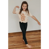 Child in Super Soft Organic Cotton Love T-shirt showing playful pose with dark pants