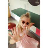 Playful kid in pink sunglasses and shirt showcasing the Gingham All Day Twirl Dress