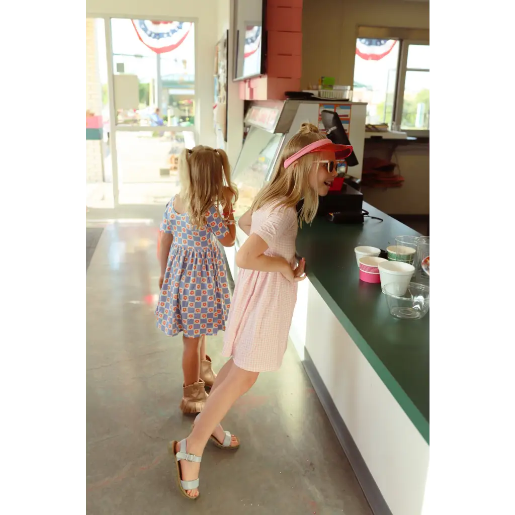 Two customers in summer dresses at a counter, showing off the Gingham All Day Twirl Dress