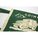 Green home pennant with John Muir design and off-road vehicle in a mountain setting