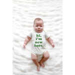 Baby wearing a Hi I’m New Here Baby Onesie in Organic Cotton Sage with green text
