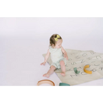 Baby enjoying the Hummingbird Pocket Playsuit on a colorful alphabet play mat